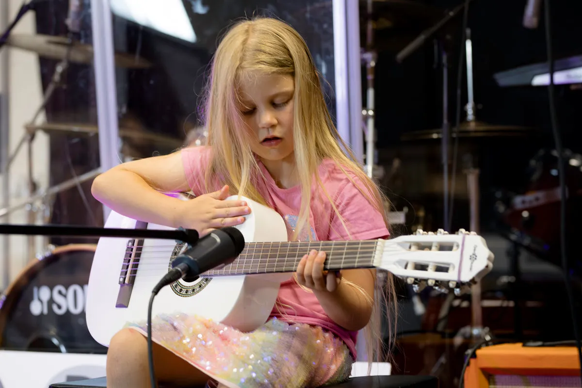 Student playing guitar during a music lesson